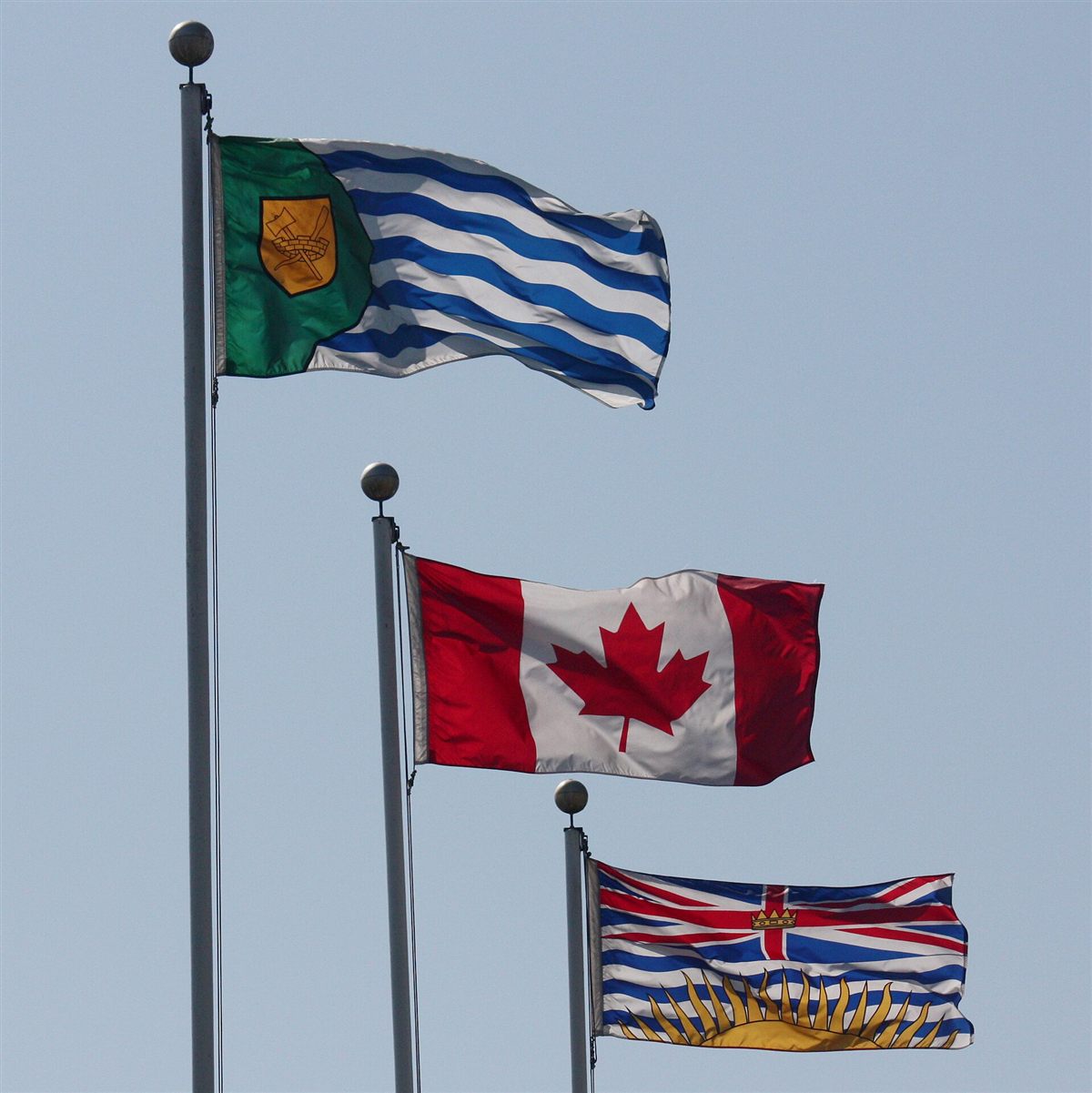 Canadian and provincial flags flying from tall flagpoles